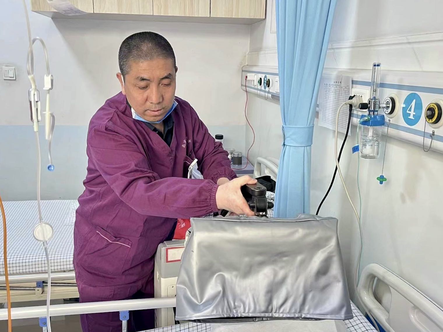 薛师傅在给患者做可见光治疗，为伤口消炎。受访者供图